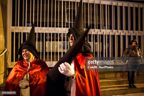 Two Nazarenes of the brotherhood of the passion are glad to have finished the night prayer procession during Holy Week in the city of Santander....