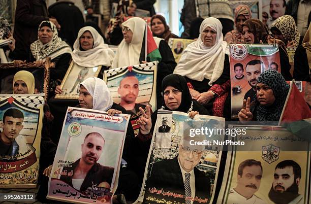 Palestinian women hold placards showing pictures during a protest demanding the release of their relatives prisoners held in Israeli jails, in front...