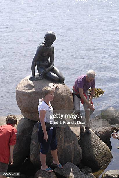 Tourists visitng little Mermaid and biy little mermaid as spuvenirs some are buy wth USA dolars bills at langeline 27 July 2011