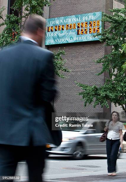 Pedestrians walk pass the National Debt Clock billboard on a building in midtown Manhattan on August 2, 2011 in the New York City. The national debt...