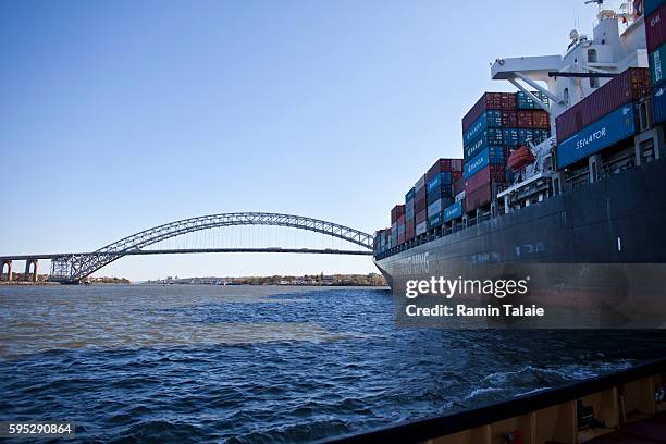 Tugboat follows the Panamanian flagged Chinese operated Yang Ming Great cargo ship as it passes under the Bayonne Bridge in New York Harbor in New...