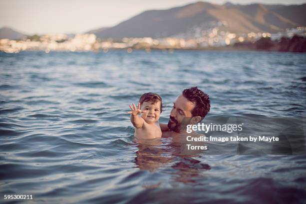 baby girl with dad having a swim at the beach - familia en la playa fotografías e imágenes de stock