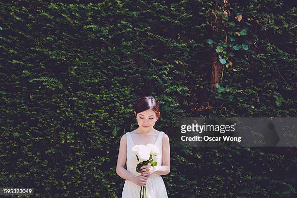 smiling shy bride holding bouquet - asian bride stock pictures, royalty-free photos & images