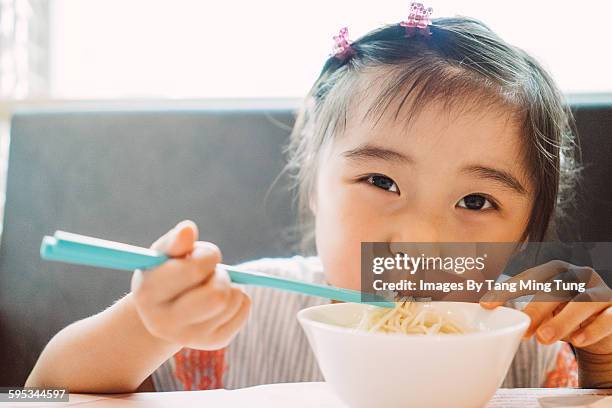 Little girl having noodle with chopsticks