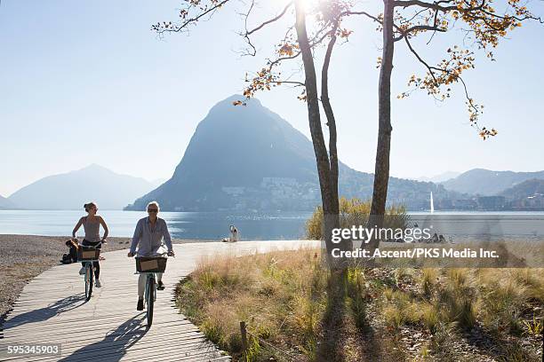 mother and daughter bike along boardwalk,lakeshore - lugano - fotografias e filmes do acervo