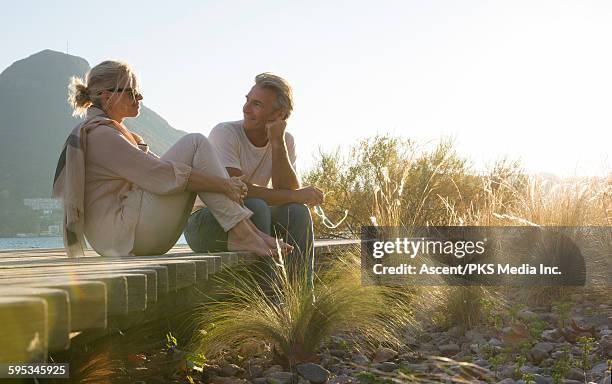 couple relax on boardwalk, at lakeshore - holzsteg stock-fotos und bilder