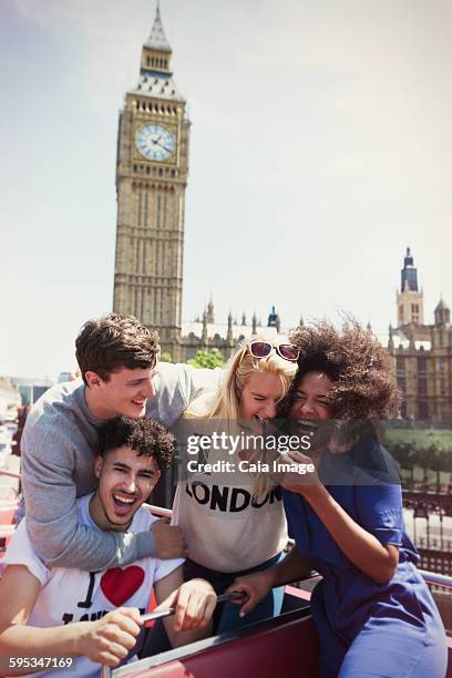 enthusiastic friends riding double-decker bus below big ben clocktower, london, united kingdom - open top bus stock pictures, royalty-free photos & images