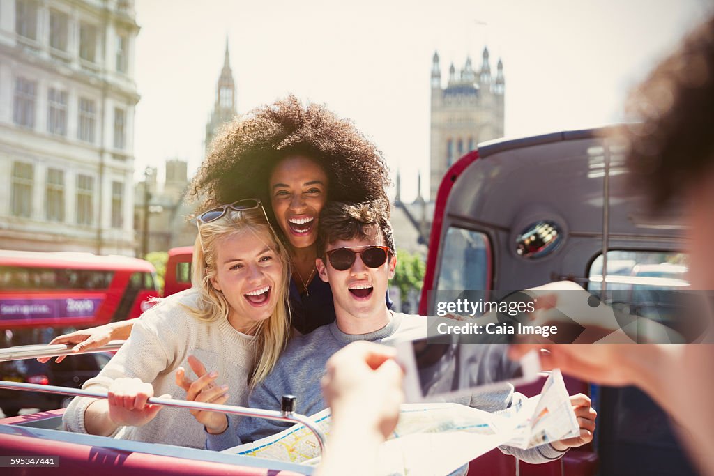 Enthusiastic friends being photographed on double-decker bus