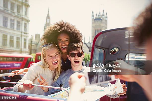 enthusiastic friends being photographed on double-decker bus - open top bus stock pictures, royalty-free photos & images