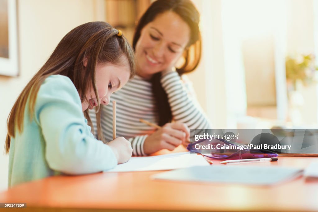 Mãe vendo filha fazer lição de casa