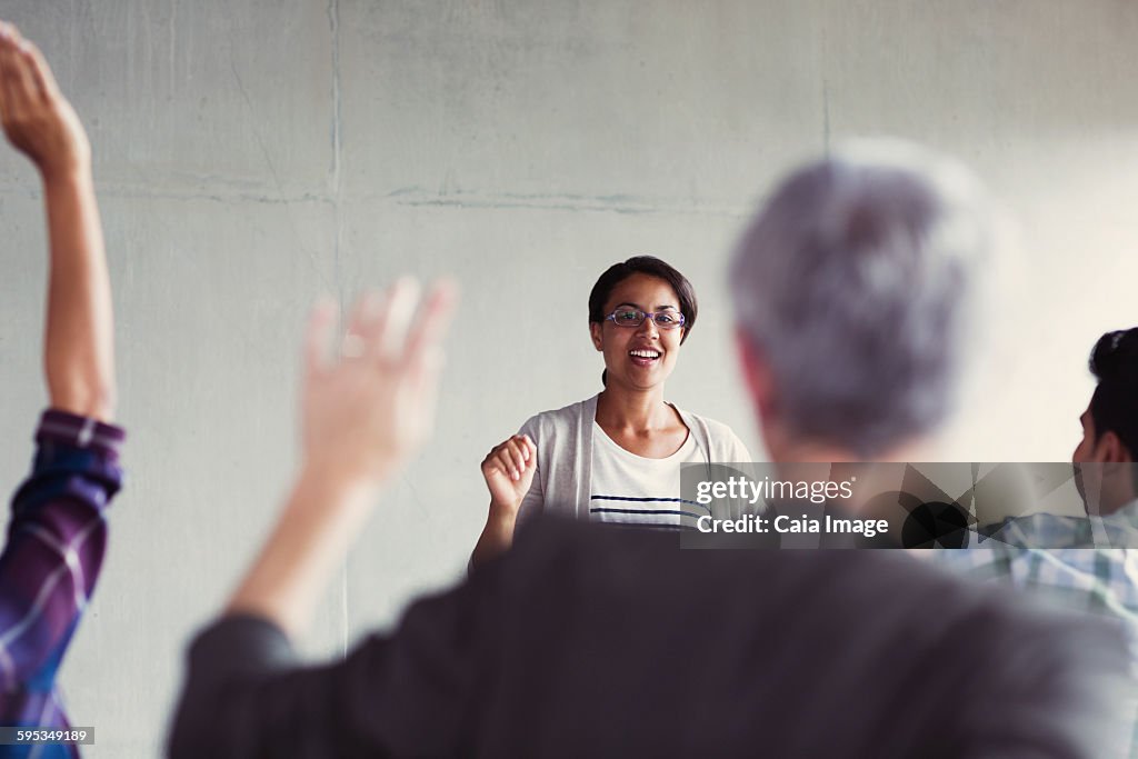 Teacher calling on students with hands raised in adult education classroom