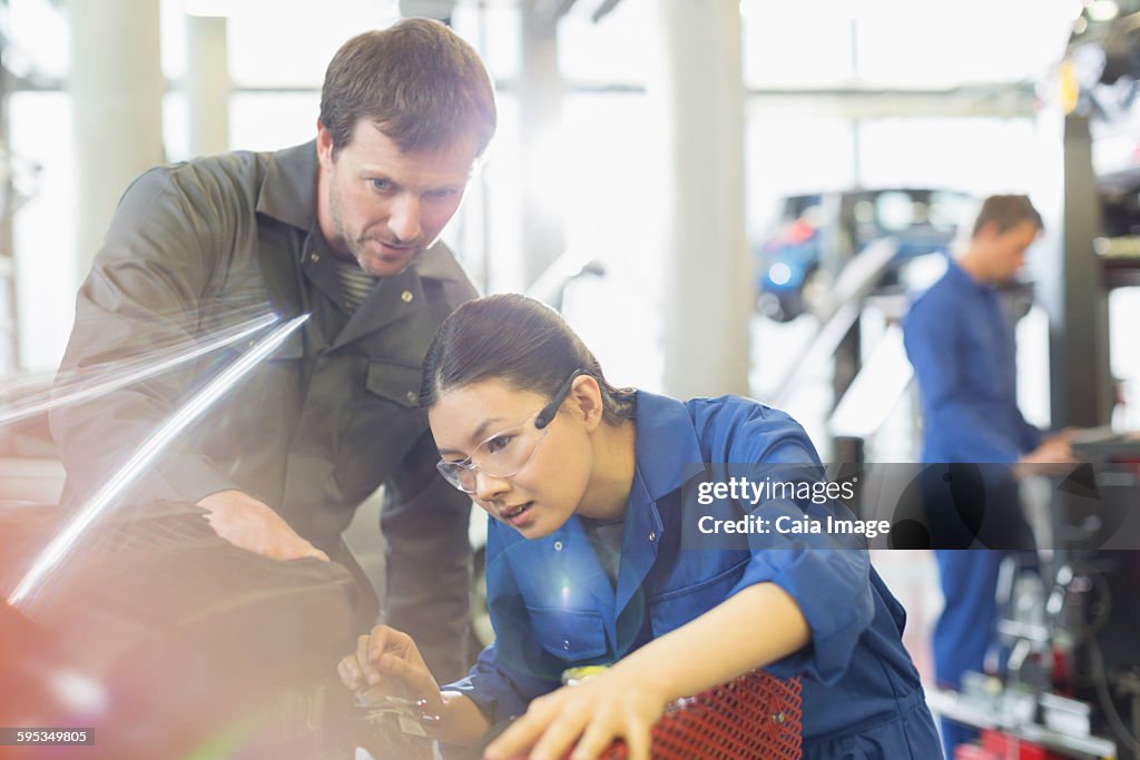 Mechanics working on engine in auto repair shop