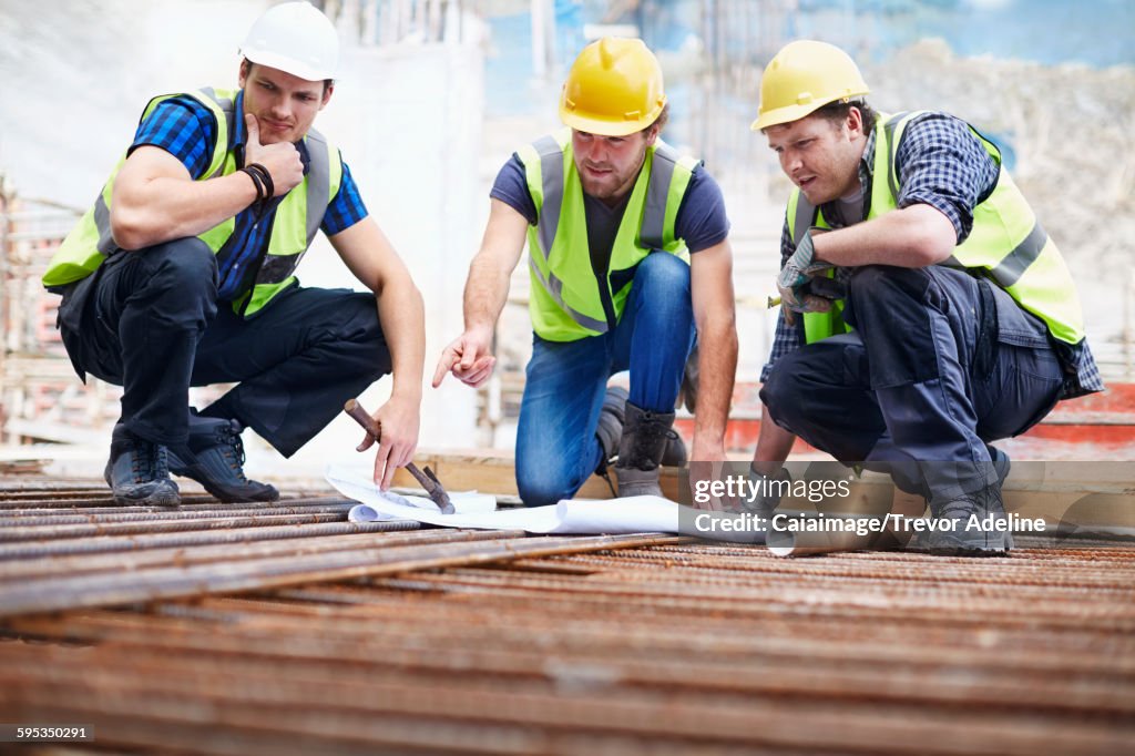 Construction workers and engineer reviewing blueprints at construction site