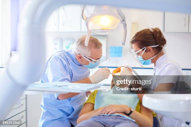 dental team performing procedure - tandhälsa bildbanksfoton och bilder