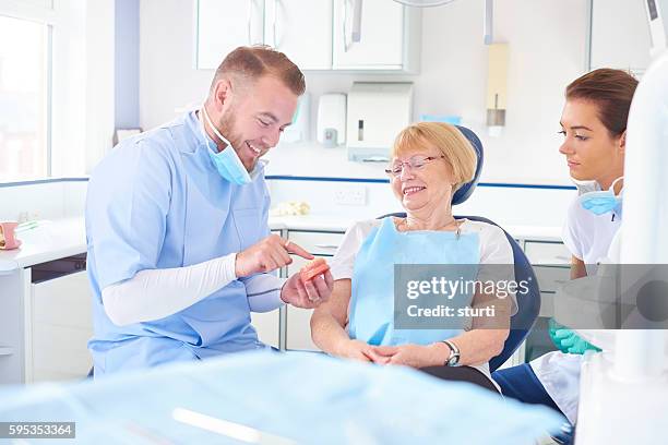 dentist showing senior patient model of dentures - dentures 個照片及圖片檔