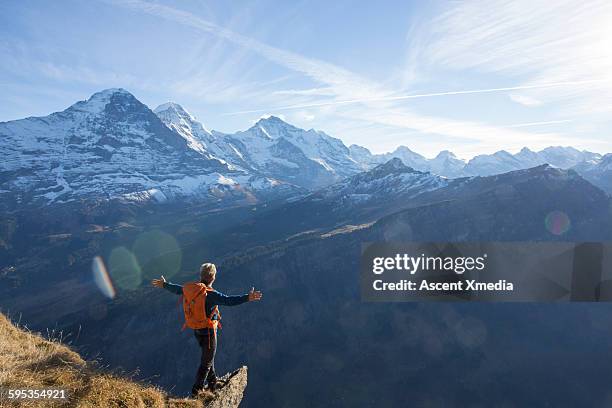 hiker extends arms outwards on summit ridge - leading edge stock pictures, royalty-free photos & images