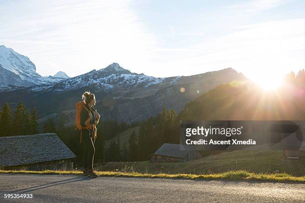 female hiker pause to watch sunrise, mountain road - mountain road stock pictures, royalty-free photos & images