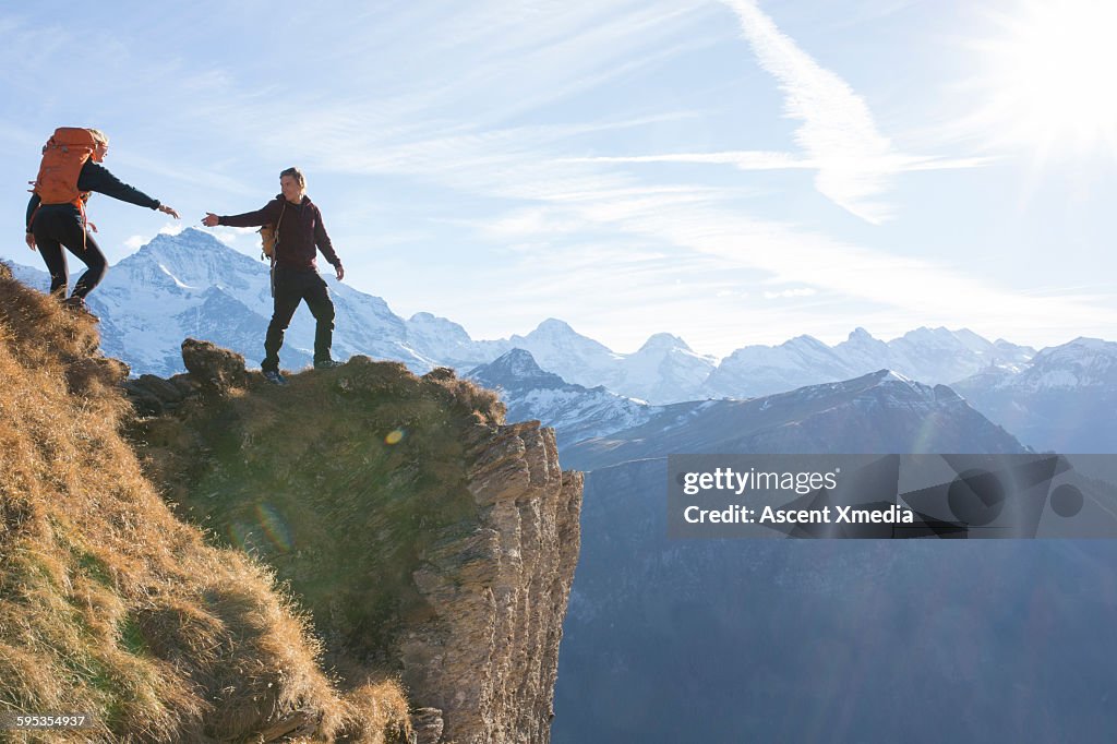 Hiker offers companion a helping hand, above mtns