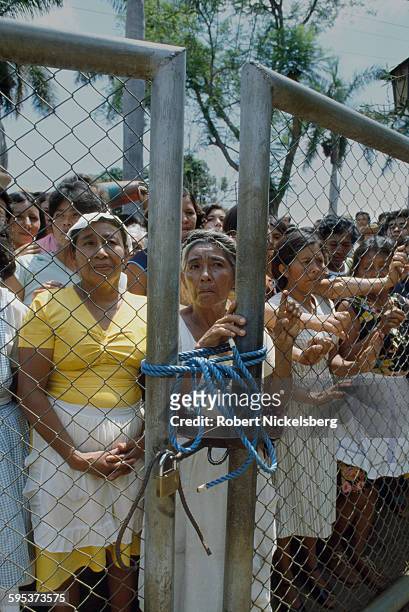 View, through a chain-link fence, of people as they wait to vote in the Salvadoran presidential and legislative election, San Salvador, El Salvador,...