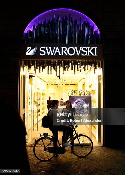 Two women stop to talk outside a Swarovski jewelry and fashion accessories store in Florence, Italy. Founded in 1895 in Austria, Swarovski designs...