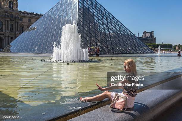 Woman cool off in fontain in Paris near the Louvre museum on a hot day on August 25, 2016.