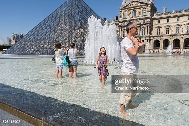 People cool off in fontain in Paris near the Louvre museum on a hot day on August 25, 2016.