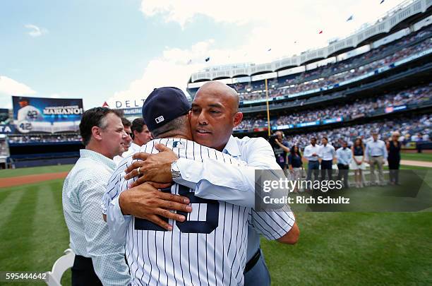 Manager Joe Girardi of the New York Yankees and former closer Mariano Rivera hug after a monument plaque ceremony honoring Rivera before a game...