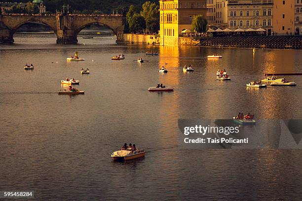charles bridge(karlův most) and little boats at the vltava river in center prague, czech republic, europe - tancici dum stock pictures, royalty-free photos & images