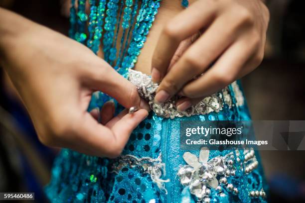 young woman securing sequined dress with safety pin - vestido de fiesta fotografías e imágenes de stock