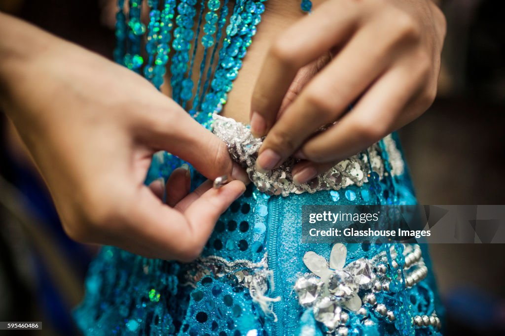 Young Woman Securing Sequined Dress With Safety Pin