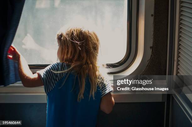 young girl looking out train window - girl train window stock pictures, royalty-free photos & images