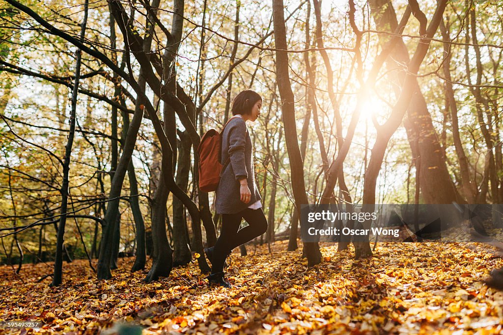 Woman with back pack walking through woodland