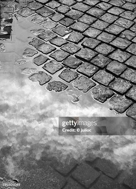reflected clouds on a water puddle - portugees straatmozaïek stockfoto's en -beelden