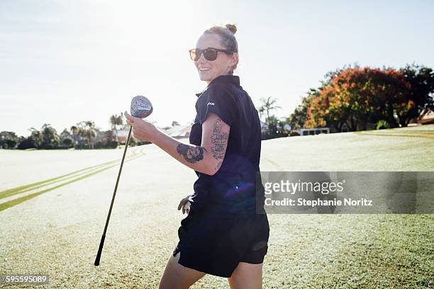 smiling woman on golf course with golf club - golf club stock-fotos und bilder