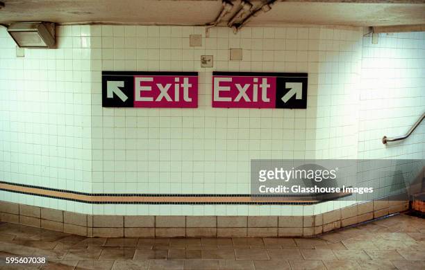 two subway exit signs pointing in opposite directions - exit sign photos et images de collection