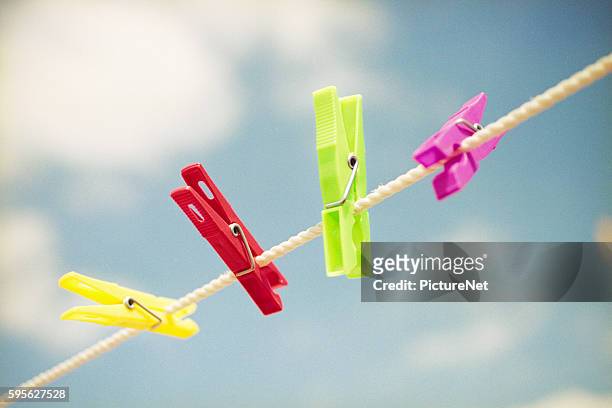 colorful clothespins on clothesline - wäscheklammer stock-fotos und bilder