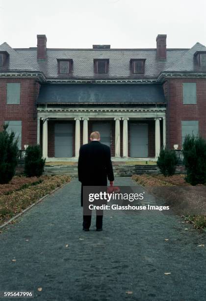 man with stuffed animal standing by old mansion - homecoming stock pictures, royalty-free photos & images