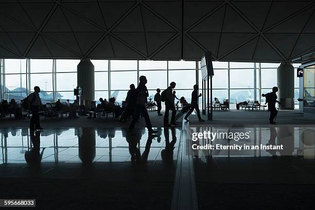 crowd traveling through a busy airport. - huddle foto e immagini stock