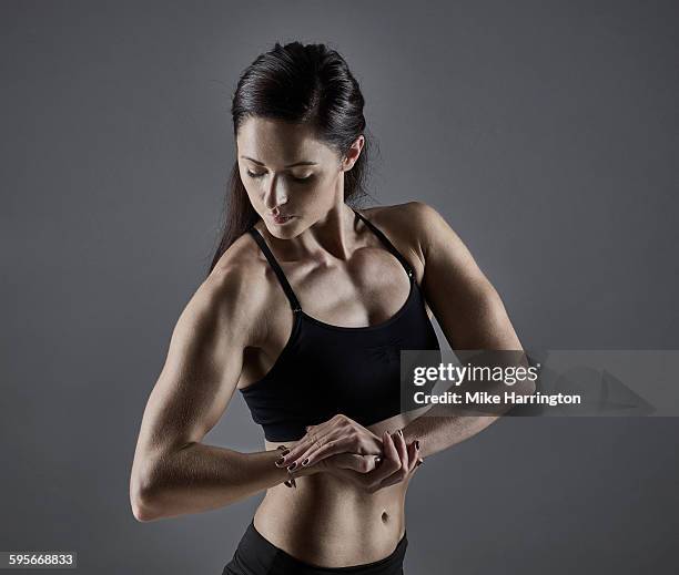 young, muscular female tensing bicep - bodybuilder flexing biceps stock pictures, royalty-free photos & images