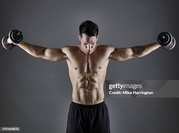 young athletic male bodybuilder lifting dumbbells - chest torso stockfoto's en -beelden