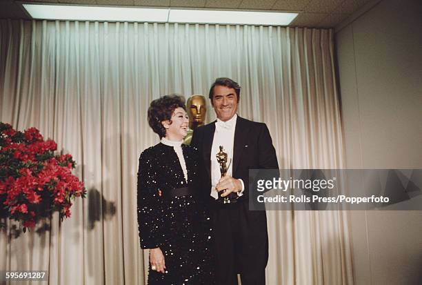 American actress Rosalind Russell pictured standing with American actor Gregory Peck at the 40th Academy Awards at the Santa Monica Civic Auditorium...