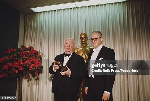 English film director Alfred Hitchcock pictured left, standing with American film director Robert Wise at the 40th Academy Awards at the Santa Monica...