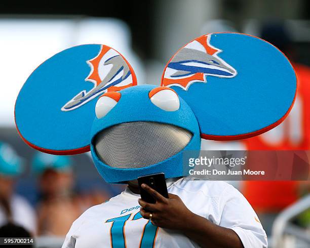Fan of the Miami Dolphins wears a Mickey Mouse ears with the Dolphins colors and logo on them during a preseason game against the Atlanta Falcons at...