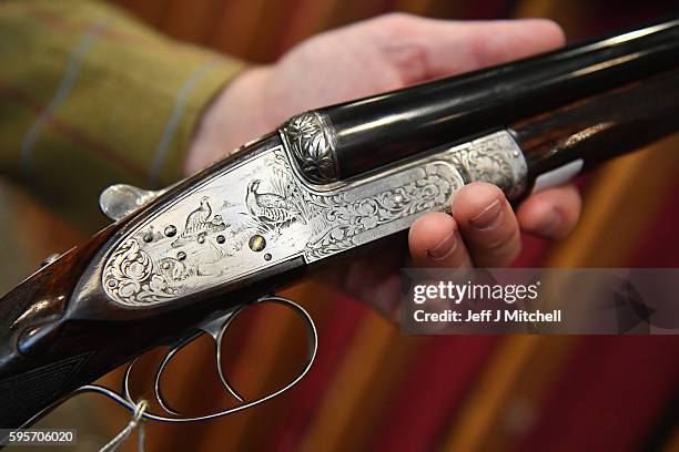 Auctioneer Gavin Gardiner holds a 12-bore Royal de Luxe model self-opening sidelock ejector gun by Holland and Holland at Gleneagles Hotel on August...