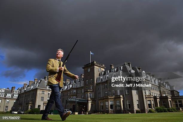 Auctioneer Gavin Gardiner holds a 12-bore 'Royal de Luxe' model self-opening sidelock ejector gun by Holland and Holland at Gleneagles Hotel on...