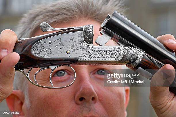 Auctioneer Gavin Gardiner holds a 12-bore 'Royal de Luxe' model self-opening sidelock ejector gun by Holland and Holland at Gleneagles Hotel on...