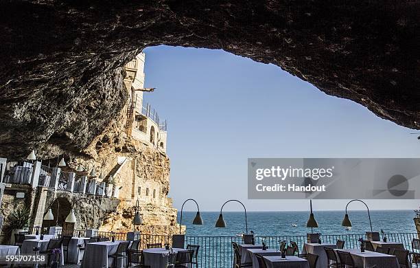 In this handout image provided by Red Bull, Artem Silchenko of Russia dives from the city cliffs during a 22 person "domino dive" prior to fifth stop...