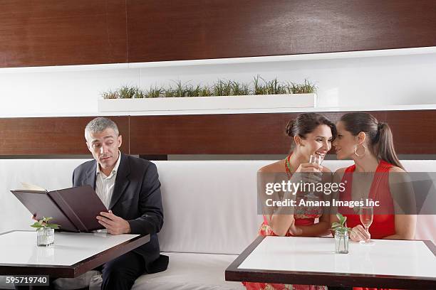 man listening to two women whispering in restaurant - lauschen stock-fotos und bilder