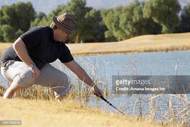 man looking for golf ball in pond - cross golf stockfoto's en -beelden