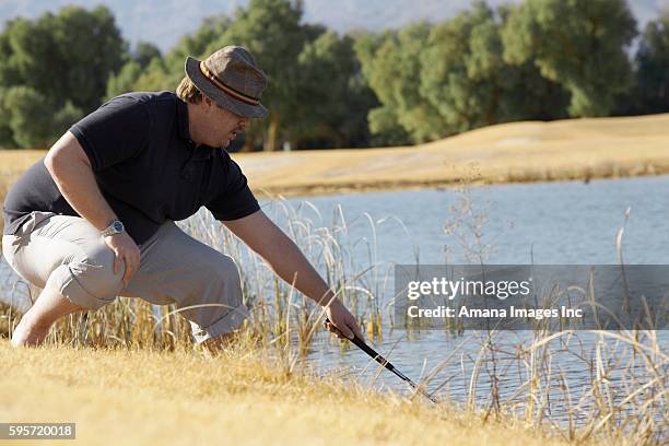 man looking for golf ball in pond - angry golfer stock pictures, royalty-free photos & images